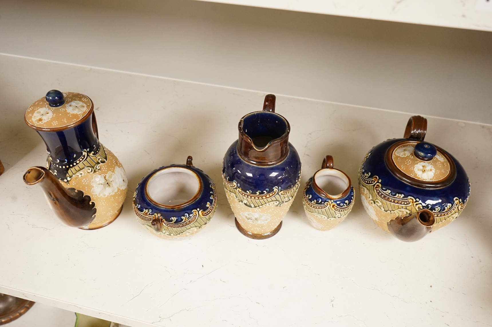 A small collection of Doulton Lambeth stoneware comprising, tea and coffee pots, two jugs and sugar bowl, largest 21cm high